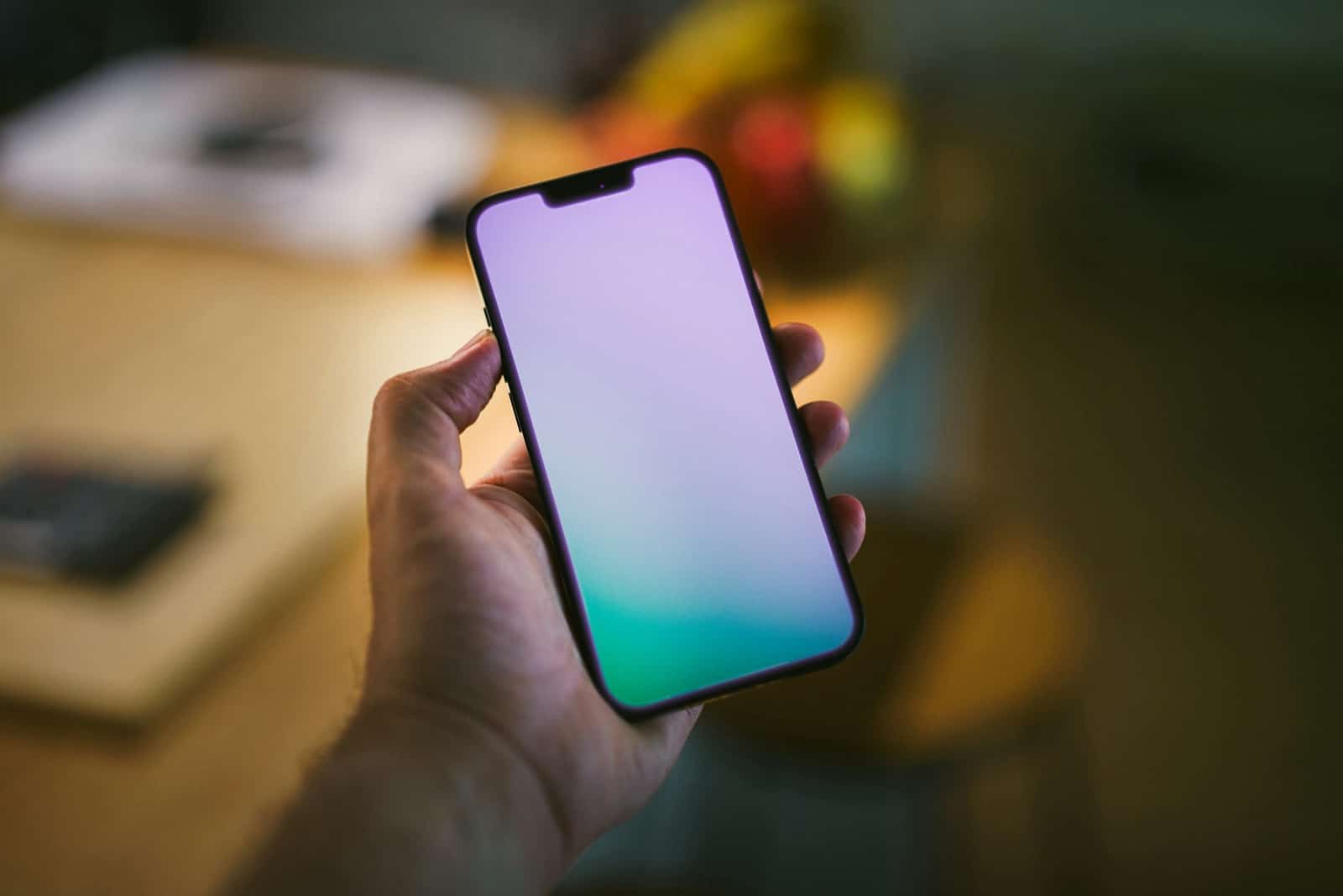 Main tenant un smartphone pour piloter la domotique de la maison, intérieur en arrière-plan