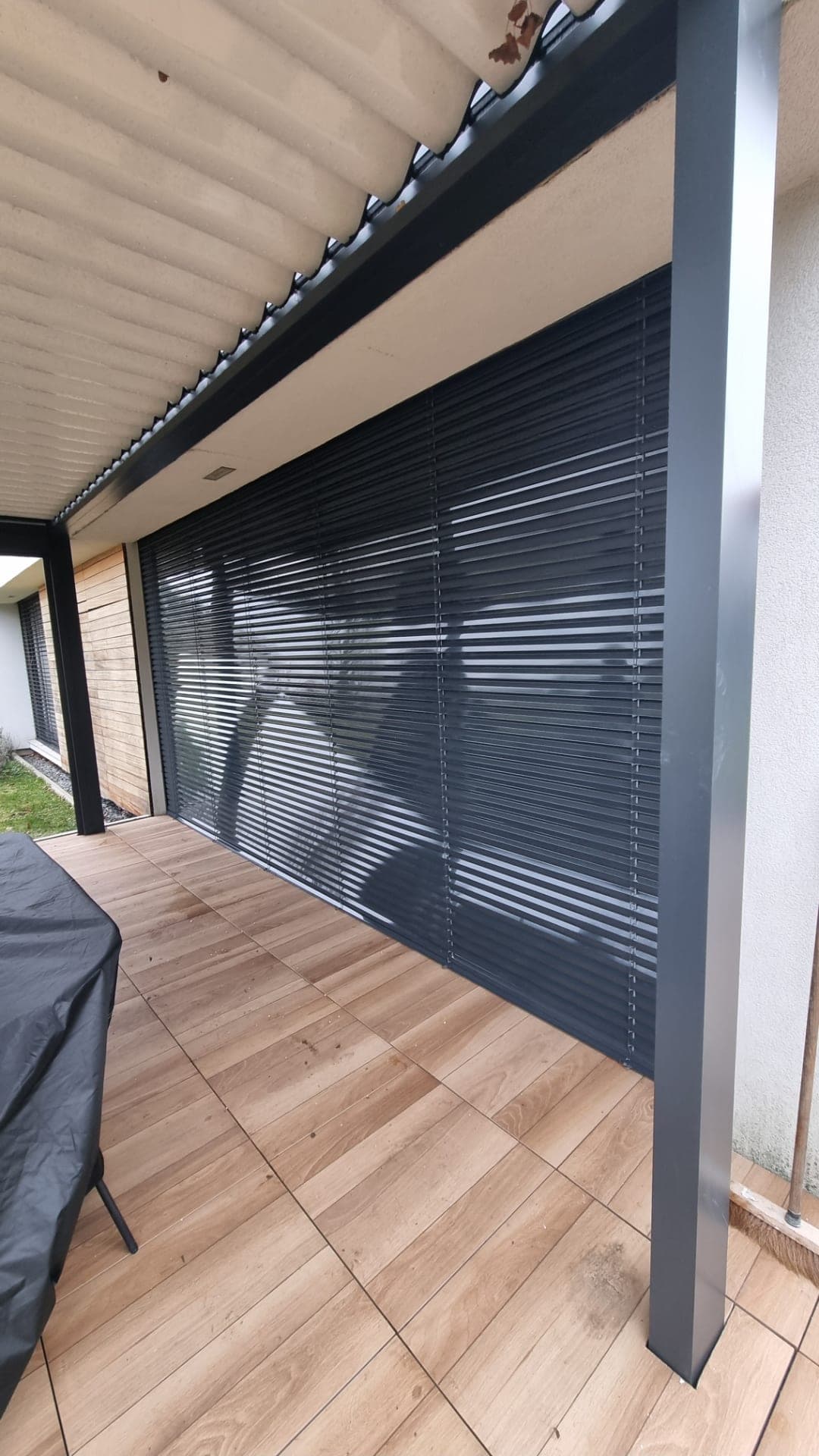 Brise-soleil orientable anthracite descendu devant une baie vitrée sous une terrasse couverte