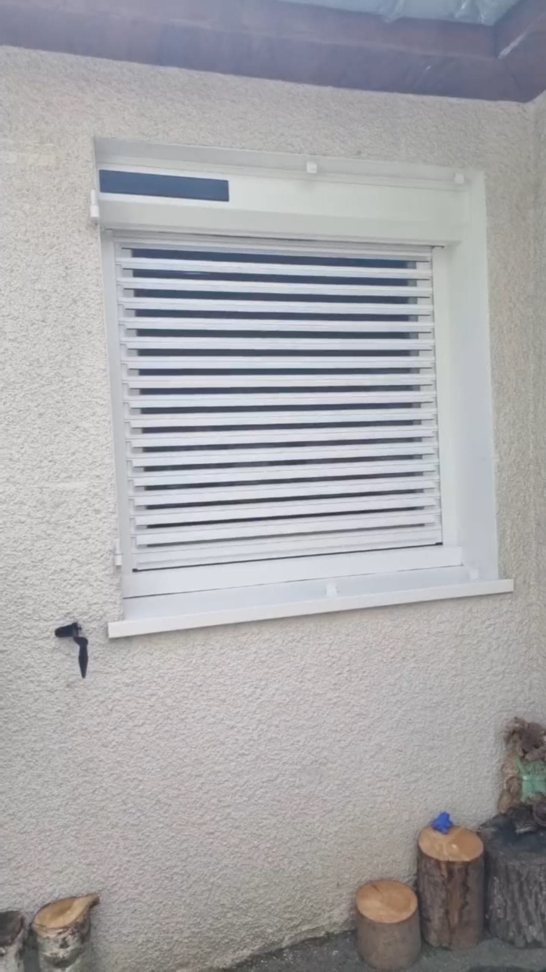 Brise-soleil orientable blanc posé sur une fenêtre de façade crépie