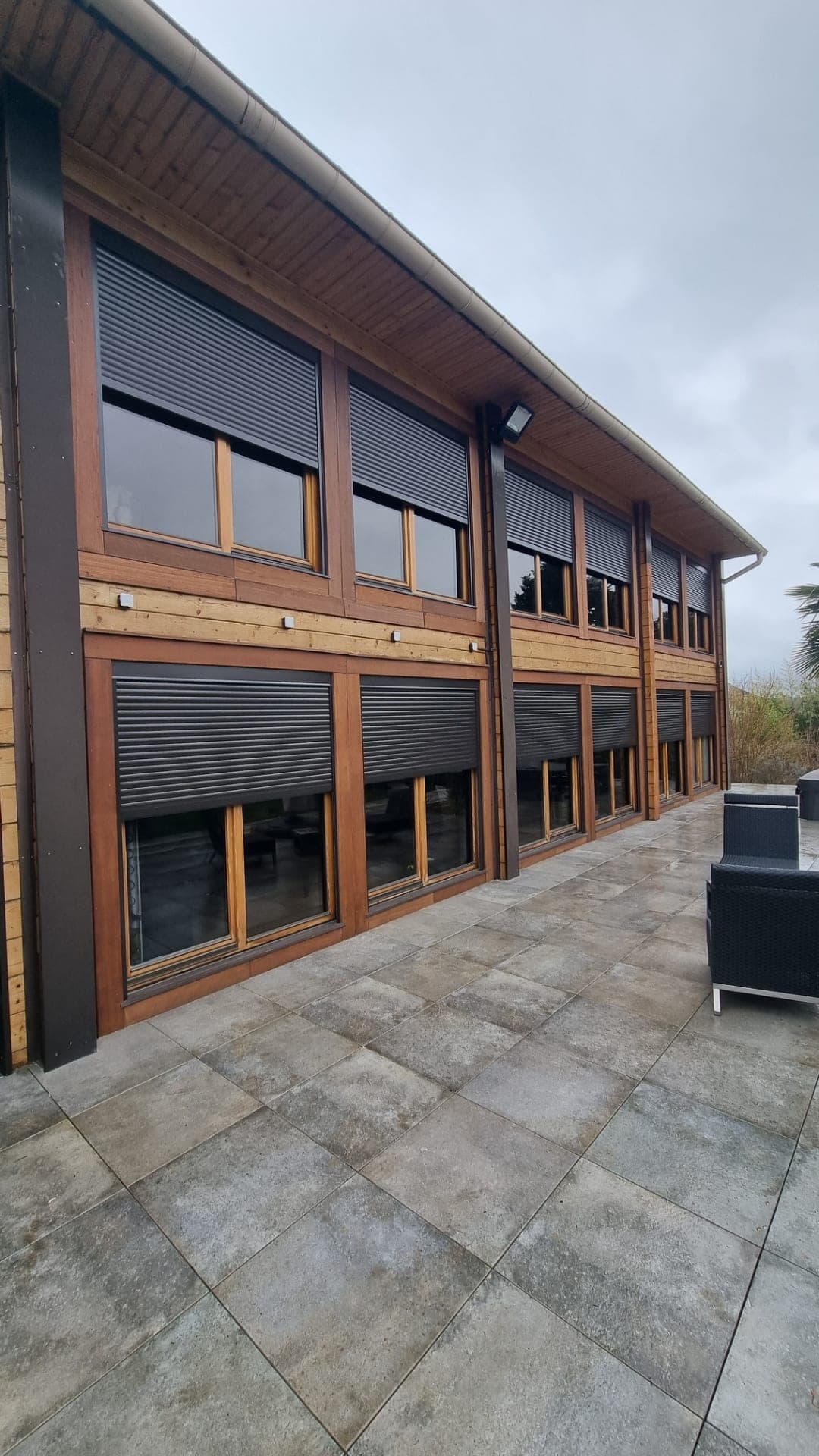 Façade à bardage bois équipée de volets roulants aluminium anthracite sur deux niveaux