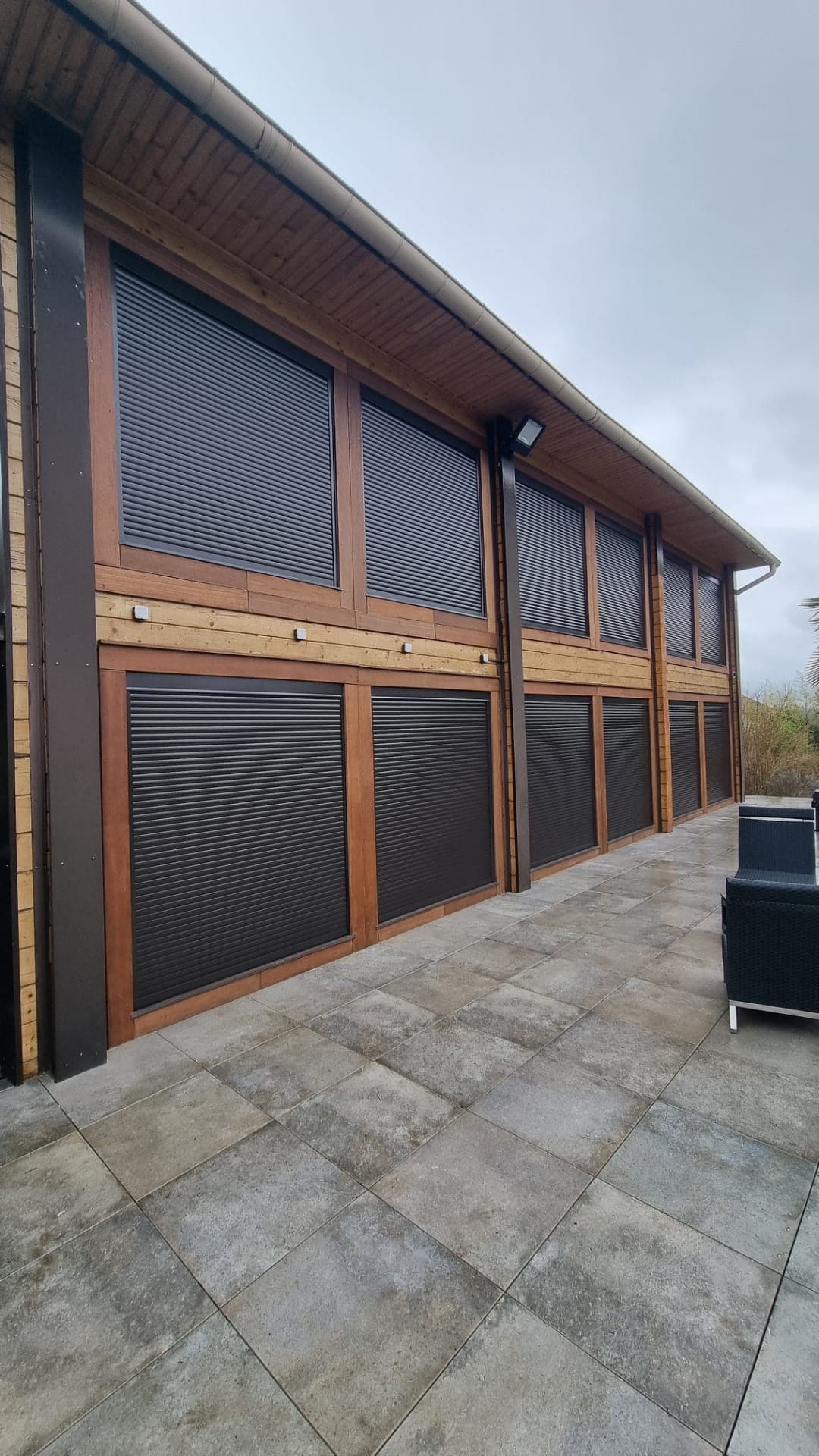Volets roulants anthracite posés sous linteau sur une façade à bardage bois