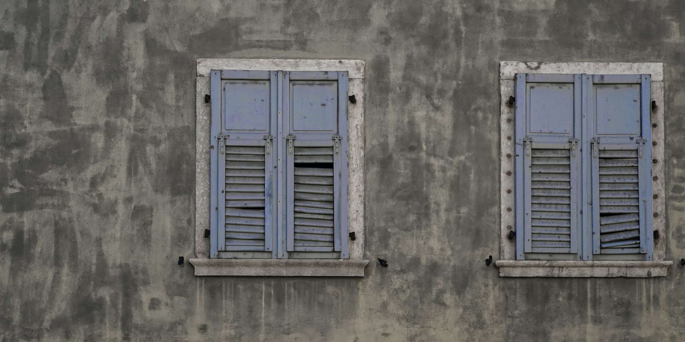 Volets battants en bois fermés sur un mur en crépi